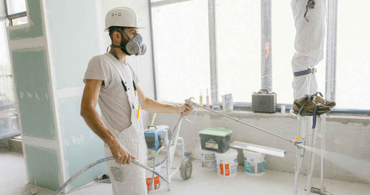 Painter wearing safety gear and using professional tools during professional painting services in a commercial space.