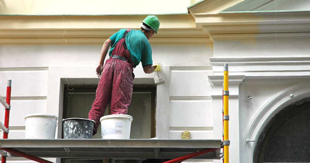 Professional painter working on the exterior of a commercial building for a fresh look in 2025.