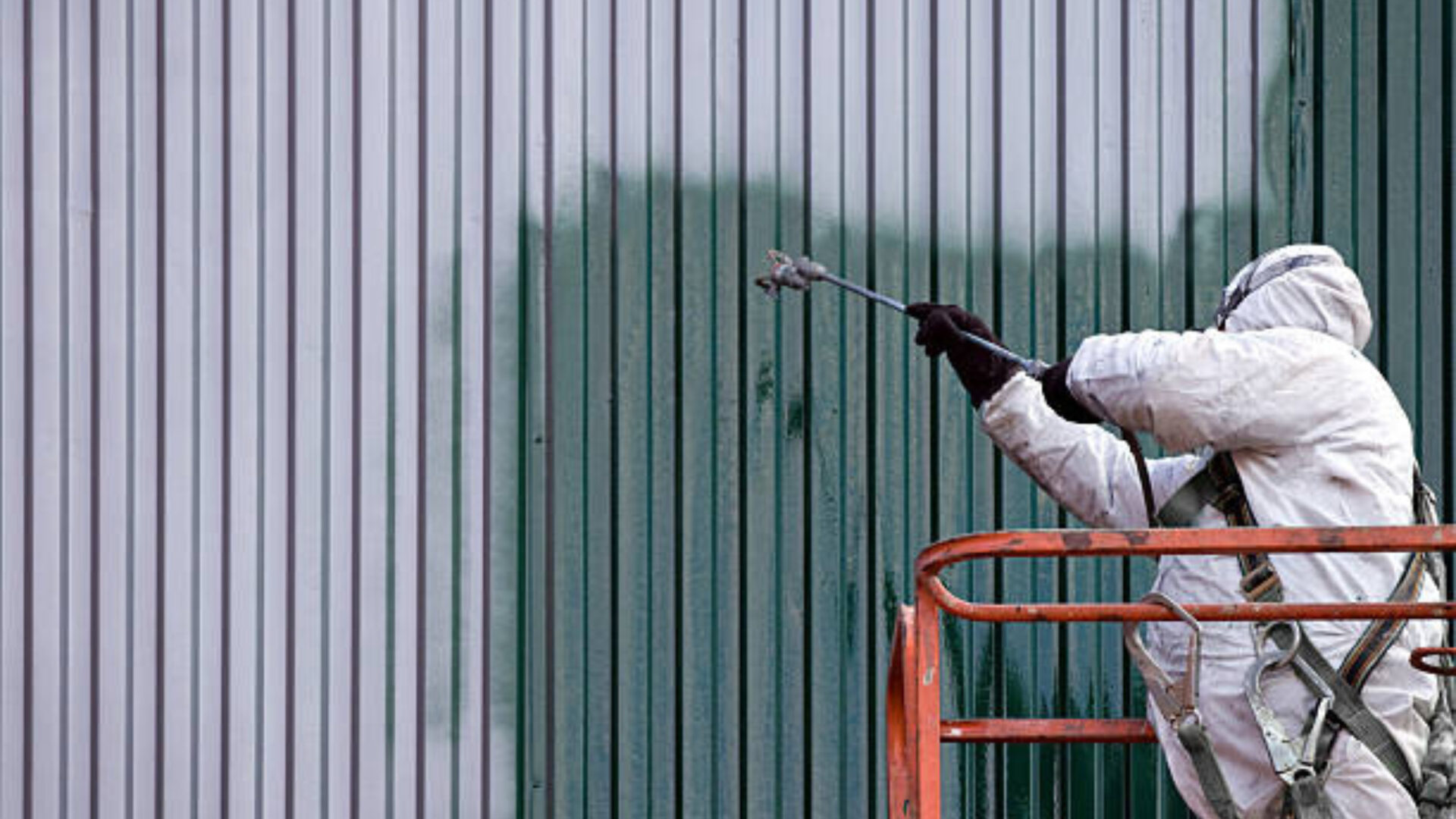 Professional commercial painting contractor applying industrial-grade coating to a metal exterior for long-lasting protection